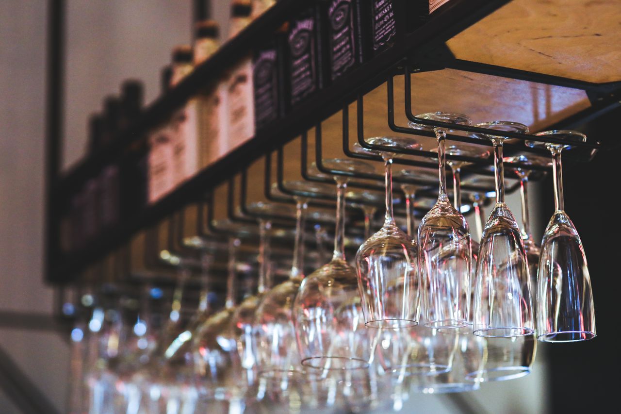 A sleek display of hanging wine glasses in an upscale bar interior.
